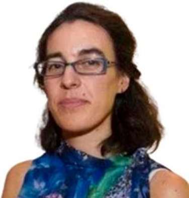 Hombre con gafas y barba de pelo oscuro con bata blanca sobre camisa azul, sentado. 